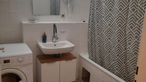 A bathroom with a washing machine, a sink, a mirror, and a shower. - Metropolitan Charm: Stylish 2+1 Apt@ Vienna's Core (Vienna)