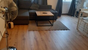 A living room with a sofa, a coffee table, a standing fan, and a floor lamp. - Metropolitan Charm: Stylish 2+1 Apt@ Vienna's Core (Vienna)