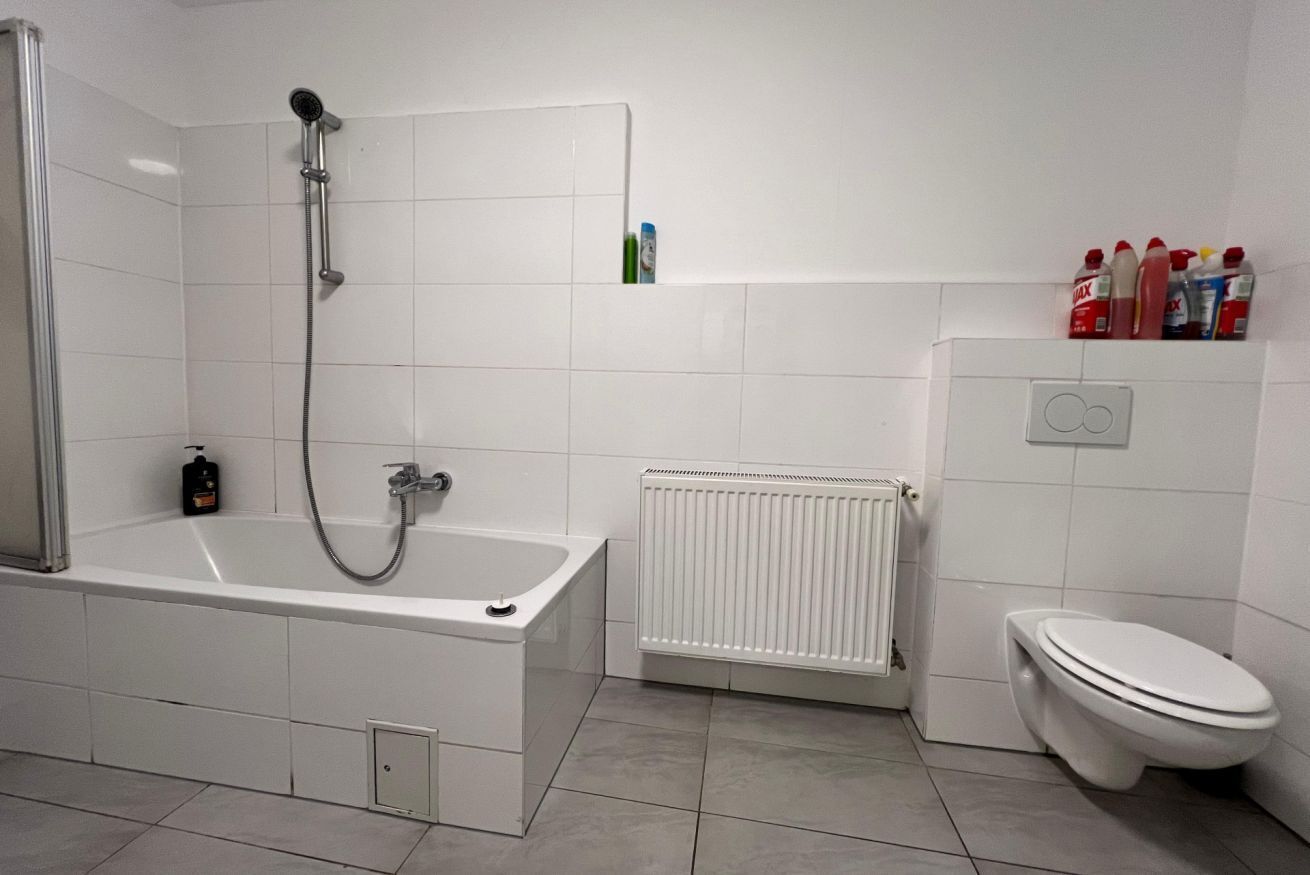 A bathroom with a bathtub, a toilet, a shower, and a radiator.