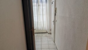 A corridor with a tiled floor, a door with a handle, and a window with sheer curtains. - Smart 2BR Apt. Perfect for Longstays near Rennweg (Vienna)