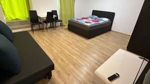 Una habitación con una cama, un escritorio, dos sillas y un televisor.