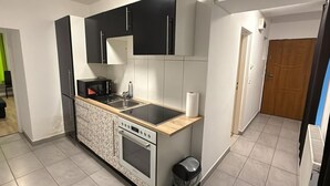 Una cocina compacta con microondas, horno, fregadero y armarios negros.