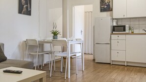 Una cocina moderna con armarios blancos, microondas y un comedor con mesa y sillas.