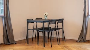 A dining table with four chairs, a vase with flowers, and a window with curtains.