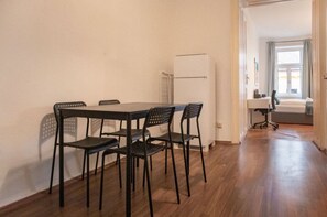 A dining area with a table and chairs, a refrigerator, and a window with curtains.