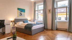 A bedroom with a bed, bedside table, lamp, and a window with curtains.