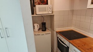 A compact kitchen with a microwave, coffee maker, and stove.