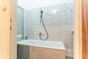 Een badkamer met een bad, een douchekop en een toilet.