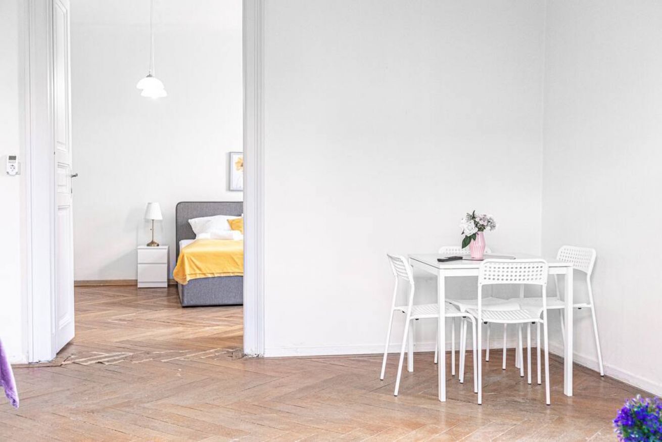 Une pièce comprenant un lit, une table de chevet, une lampe, ainsi qu’un coin repas avec des chaises et une table.