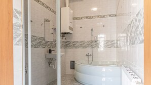 A bathroom with a glass shower enclosure, a bathtub, a sink, and a toilet.