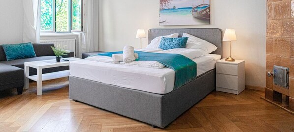 Une chambre moderne avec un grand lit, des tables de chevet, un canapé et une fenêtre donnant sur un beau paysage.