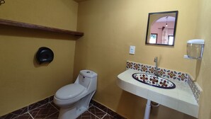 A bathroom with a toilet, sink, and mirror.