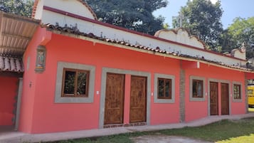 A building with a red facade, multiple wooden doors, and a tiled roof.