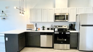 A modern kitchen with a dishwasher, stove, microwave, and refrigerator. - Cozy King 1BR w/ Pool + Gym Near EWR & MetLife (Elizabeth)