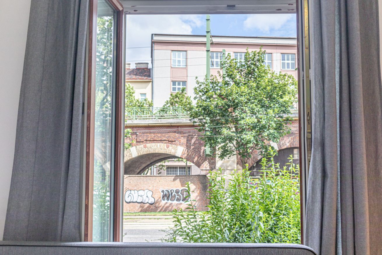 A window view of a building with a brick archway and graffiti.
