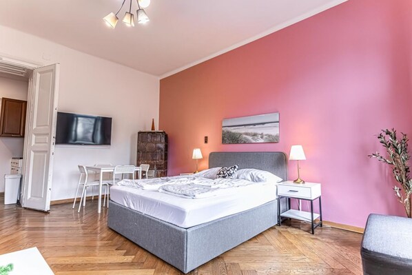 Un dormitorio con cama, mesitas de noche, escritorio, sillas y televisor.