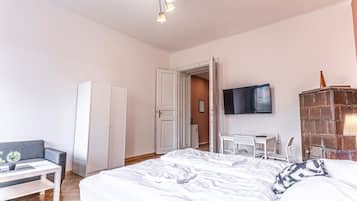 Een slaapkamer met een bed, een bureau, een stoel, een kledingkast en een televisie.