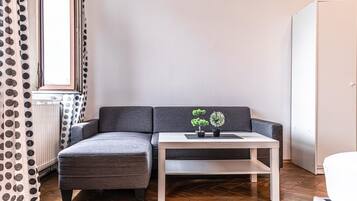 Een moderne woonkamer met een grijze bank, een witte salontafel en twee potplanten.