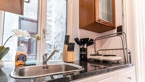 A kitchen with a stainless steel sink, a wooden cabinet, and a window with a view of a snowy landscape.