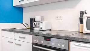 Een keuken met een magnetron, koffiezetapparaat en oven.