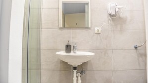 A bathroom with a white sink, a mirror, a handheld showerhead, and a glass shower enclosure. - Classy 2BR Apt. w/ Exclusive Location near AKH (Wien)