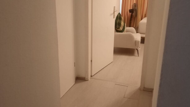 A hallway with a white door, a white chair, and a fan in the background. - Affordable 2BR Apt. Near Rennweg & Belvedere (Vienna)