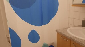 A bathroom with a sink, cabinets, and a wall with blue and green abstract designs. - Affordable 2BR Apt. Near Rennweg & Belvedere (Vienna)