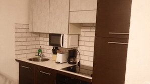 A compact kitchen with a microwave, toaster, and coffee maker on the counter, a dishwasher below, and dark wooden cabinets. - Affordable 2BR Apt. Near Rennweg & Belvedere (Vienna)
