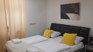 Een hotelkamer met twee bedden, een zwart hoofdeinde, een schilderij aan de muur en een nachtkastje met een lamp.