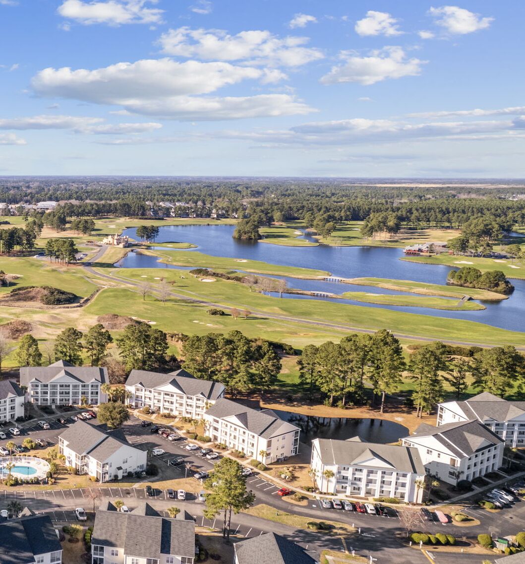 Un parcours de golf avec un lac, entouré de bâtiments résidentiels.