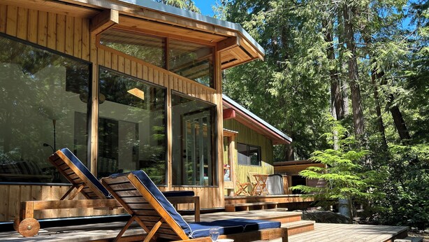 A wooden deck with lounge chairs and a table, overlooking a forested area. - Huckleberry Hideaway - an idyllic off-grid cabin on Savary Island, BC. Canada. (Lund)