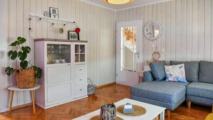 Una sala de estar con un aparador blanco, un sofá azul y una mesita con una vela.