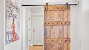 A hallway with a wooden barn-style sliding door, a white door, and a painting on the wall.