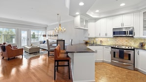 A modern kitchen with white cabinetry, a central island, stainless steel appliances, and a chandelier.