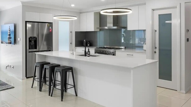 Een moderne keuken met een centraal eiland, roestvrijstalen apparatuur en een ingebouwde waterdispenser.