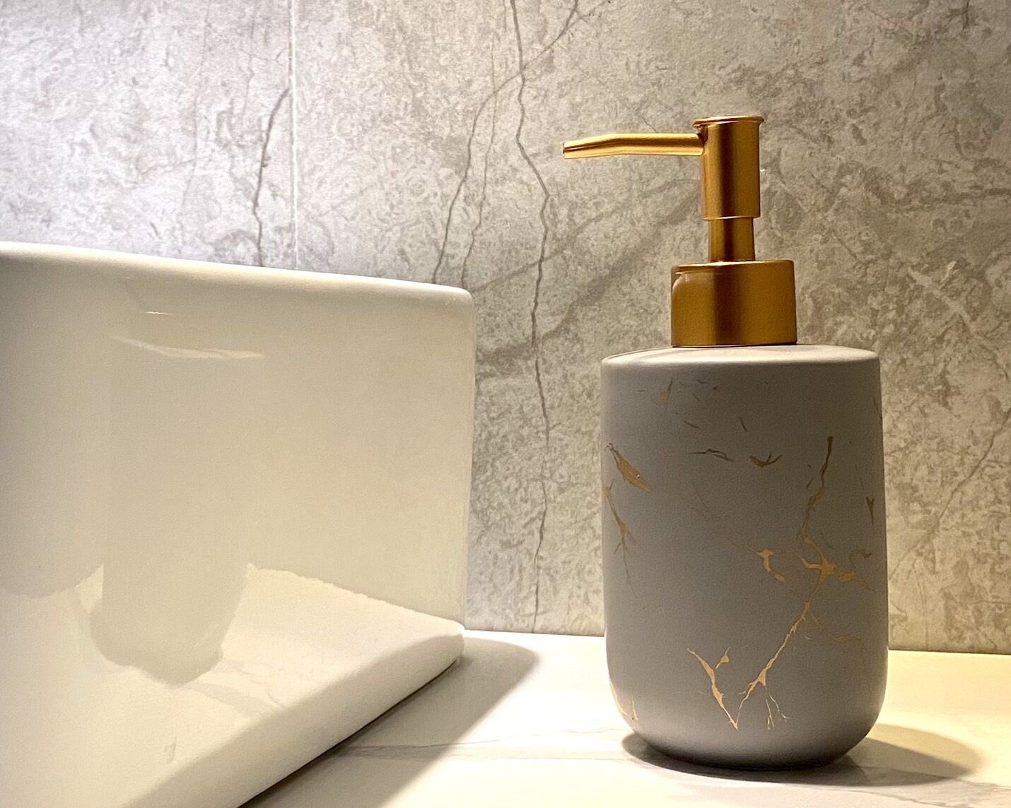 A bathroom with a white bathtub and a marble wall.
