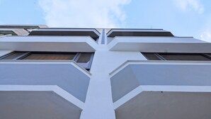Um edifício moderno com fachada simétrica, apresentando um elemento vertical central e várias janelas.