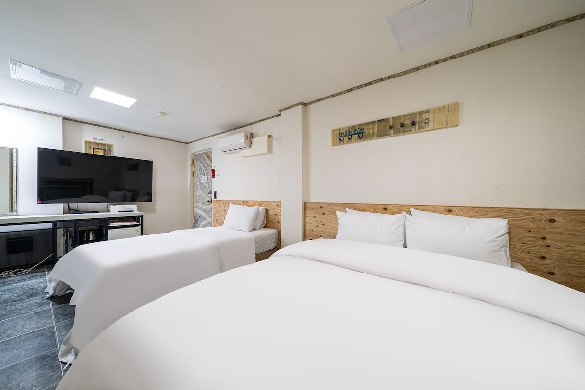 A hotel room with two beds, a TV, and a desk.