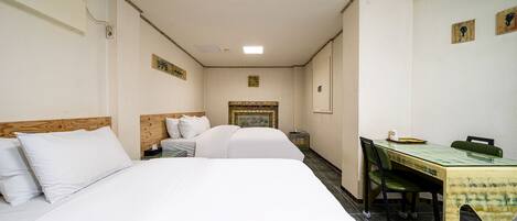 A hotel room with two beds, a small desk, and a chair.