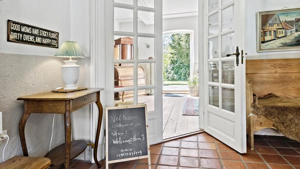 Ein rustikales Interieur mit Holztisch, einer Kreidetafel und Blick ins Freie.