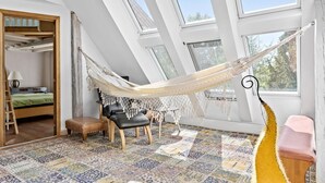 Ein Zimmer mit Hängematte, Bett, Stuhl und kleinem Tisch.