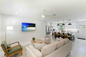 A modern living room with a sofa, a coffee table, and a TV on the wall.