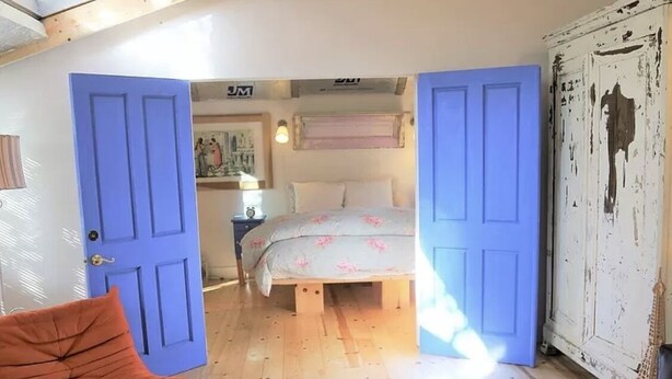 Ein Schlafzimmer mit einem Bett, einem Sessel und einem Kleiderschrank.