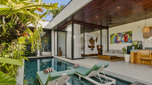 A modern pool area with lounge chairs, a glass-enclosed bedroom, and a dining area with a view of the pool. - Abhinaya Ubud Villa (Ubud)