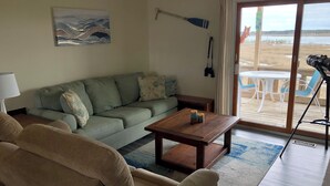 A living room with a sofa, a coffee table, and a painting on the wall. - Riptide’s Crossing:  A waterfront getaway w/deep water dock and incredible views (Chincoteague)