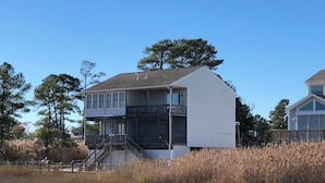 A two-story house with a balcony and a staircase leading to the second floor. - Riptide’s Crossing:  A waterfront getaway w/deep water dock and incredible views (Chincoteague)