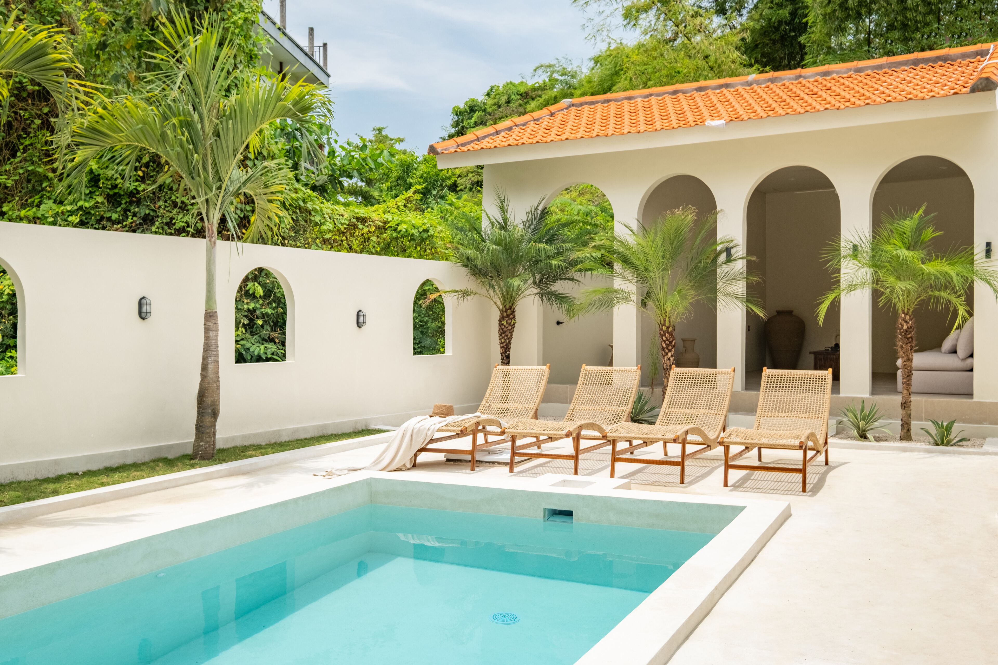 A pool area with lounge chairs and a building with arched windows.