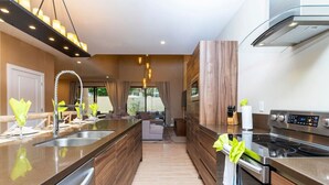 A modern kitchen with a large island, stainless steel appliances, and a view to the outdoors. - Luxury 3BDR House near Disney! (Kissimmee)