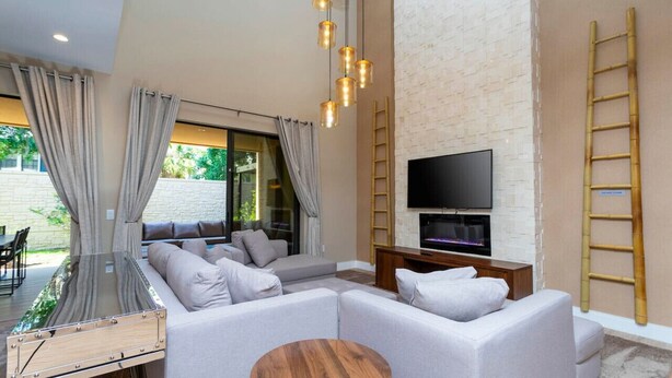 A modern living room with a sectional sofa, a TV, and a wooden coffee table. - Luxury 3BDR House near Disney! (Kissimmee)