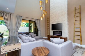 A modern living room with a sectional sofa, a TV, and a wooden coffee table. - Luxury 3BDR House near Disney! (Kissimmee)